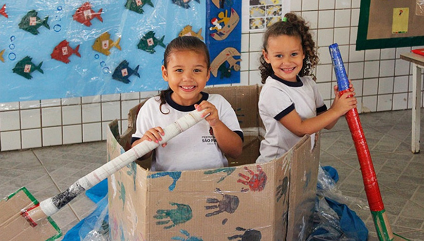 Duas meninas dentro de uma caixa de papelão, fazendo de conta que é um barco