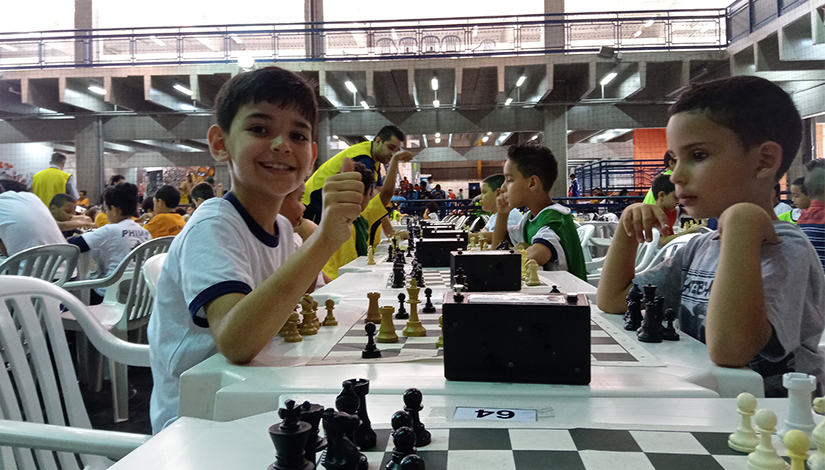 Imagem de crianças sentadas na final regional de Xadrez Individual.