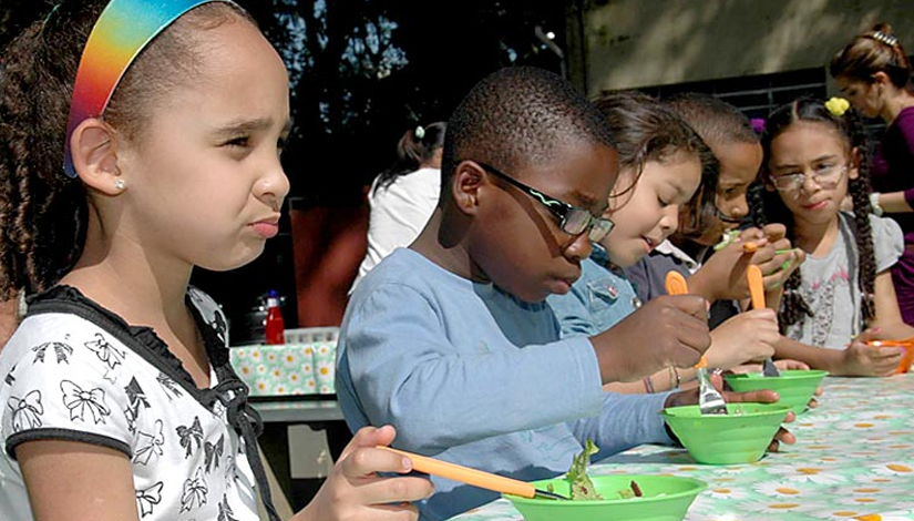 Crianças em uma mesa comendo a merenda.