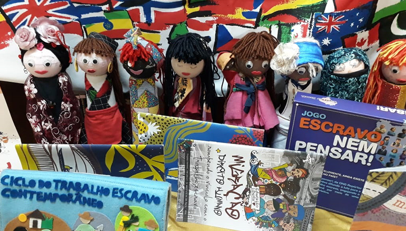 Imagem de bonecas, livros e um jogo com bandeiras desenhadas na parede ao fundo.