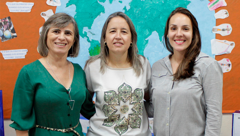 Uma fotografia com três mulheres, ao lado esquerdo, a assistente de direção, Teresa Garcia, no centro, a diretora Andrea Steinvascher, ao lado direito, a coordenadora pedagógica, Milena Martins.