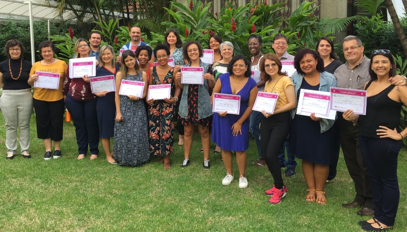 Imagem mostra 16 professores de língua inglesa da rede municipal segurando certificados de conclusão do curso posando para foto ao de representantes da Alumni na unidade Jardins da escola.