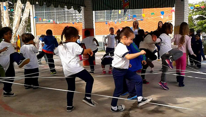 Imagem com crianças brincando em brincadeira com elástico.