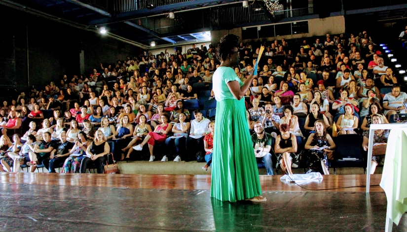 Imagem mostra teatro do CEU Jambeiro com educadores sentados participando de uma reunião pedagógica. 