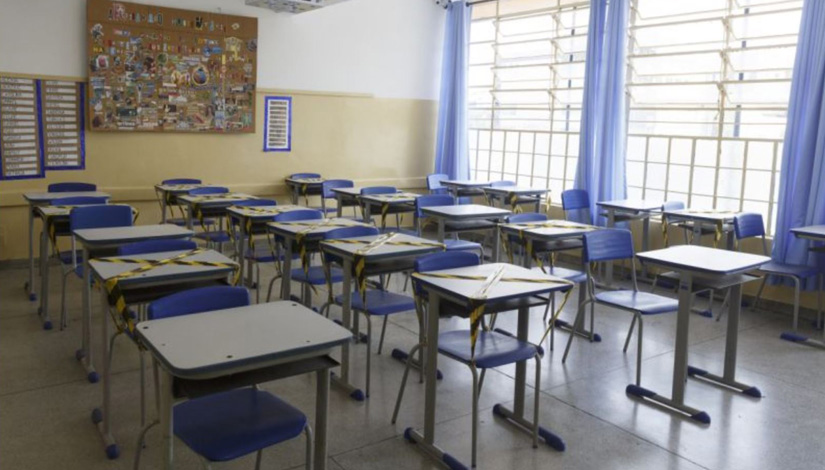 Sala de aula com carteiras e cadeiras vazias