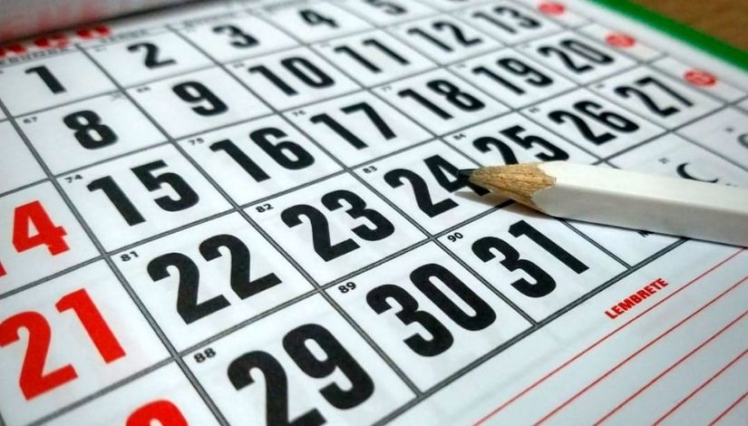 Imagem de um calendário com os dias do mês e um lápis branco sobre ele