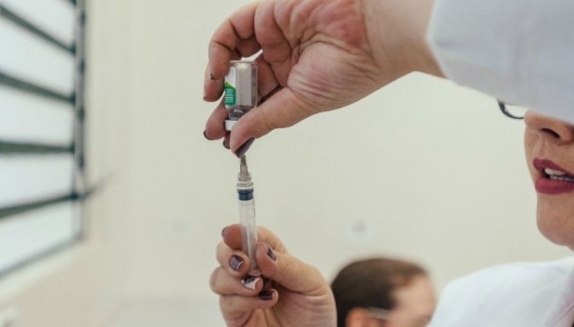 Imagem de duas mãos preparando uma vacina