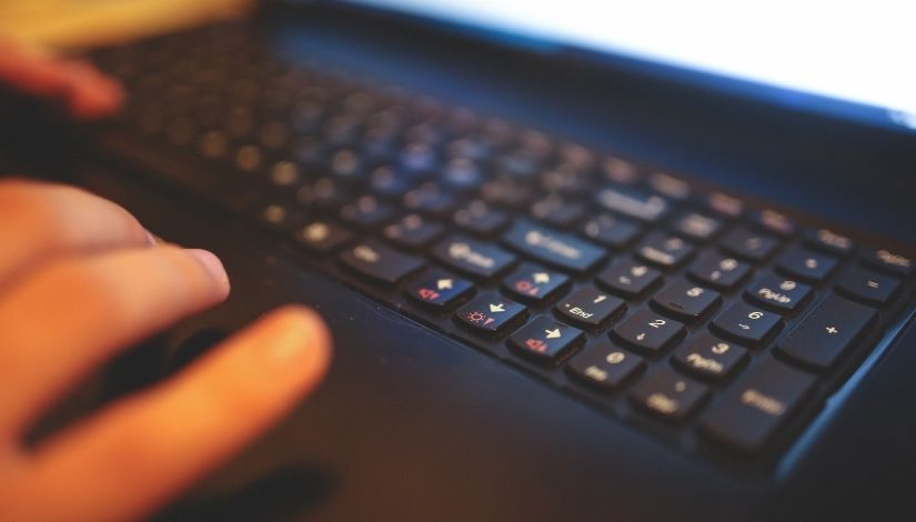 Imagem de um teclado preto com dedos da mão direita em movimento de digitação