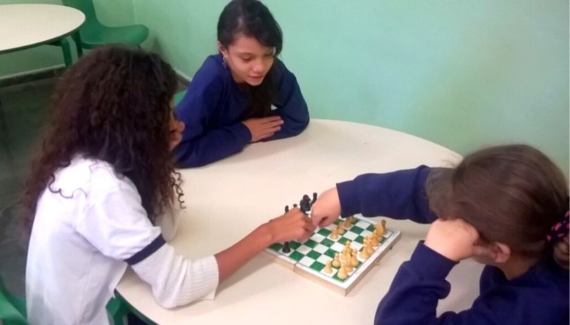 Estudantes com deficiência aprendendo Xadrez no tabuleiro com encaixe de peças.