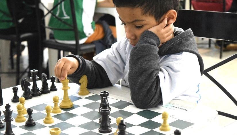 Imagem mostra estudante jogando xadrez.