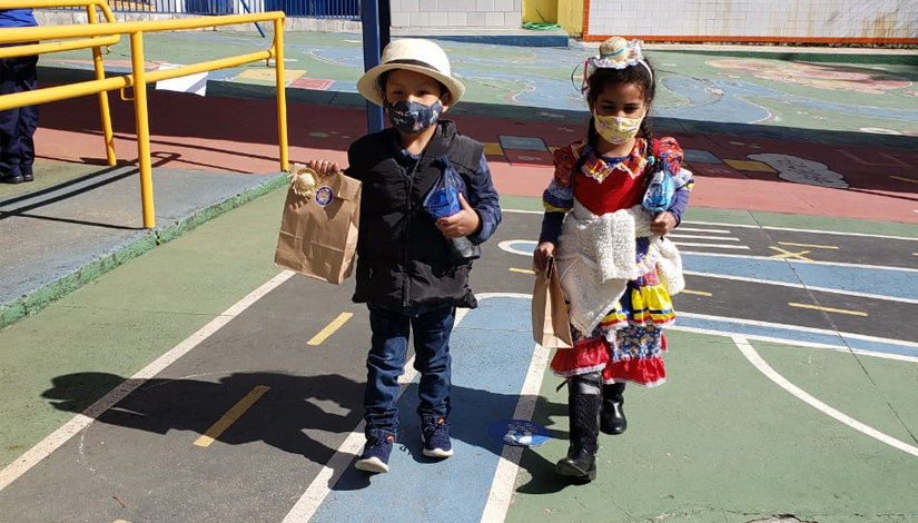 Crianças com roupa de festa junina caminham em escola
