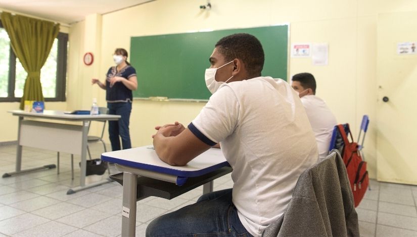 Estudantes com máscara assistem aula em sala