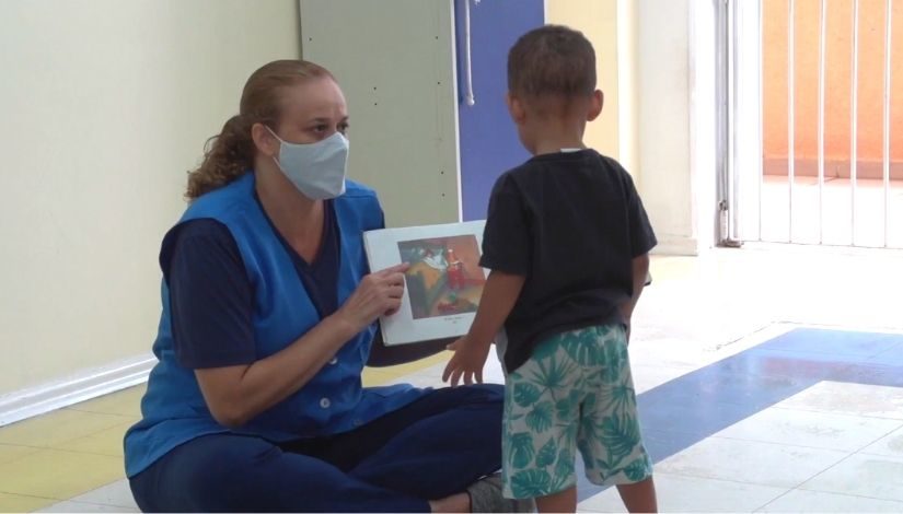 Professora de Educação Infantil mostra livro para crianças