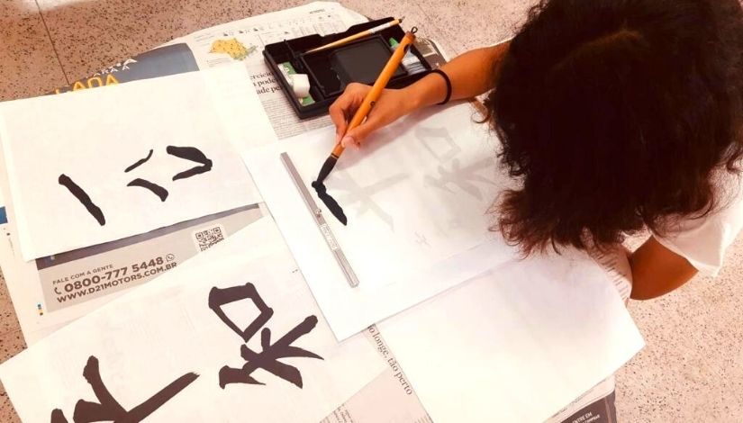 Criança fazendo caligrafia japonesa