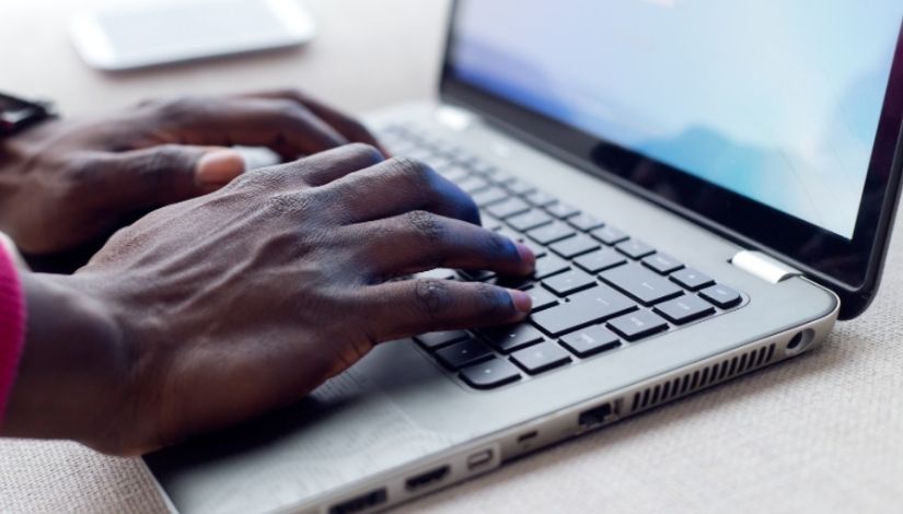 Imagem de uma mão digitando em um computador portátil.