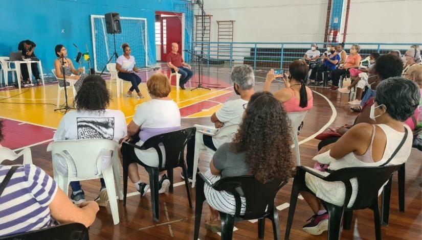 Fotografia de um grupo de pessoas participando de uma reunião com a ex atleta Daiane Dos Santos