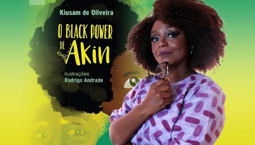 Fotografia da escritora Kiusam de Oliveira com a imagem da capa do livro 'O Black Power de Akin', de Kiusam de Oliveira, ilustrações de Rodrigo Andrade.
