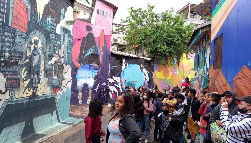 Estudantes de EMEF caminham por ruas com muros grafitados