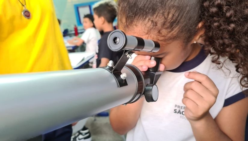 Estudante está olhando pelo telescópio.