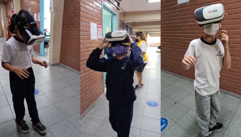 Três estudantes estão no corredor da escola usando óculos de realidade virtual.