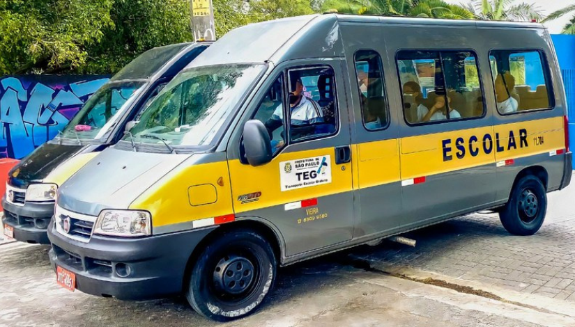 Imagem de uma perua escolar com crianças e o motorista dentro. Na porta e lateral do veículo está escrito: 