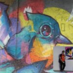 Estudantes na Bienal do Graffiti com obra de Gui Ashma, ao fundo o grafite do artista na EMEF.