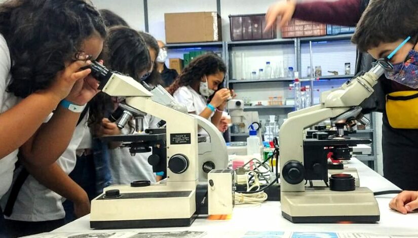 Fotografia de estudantes manuseando microscópios