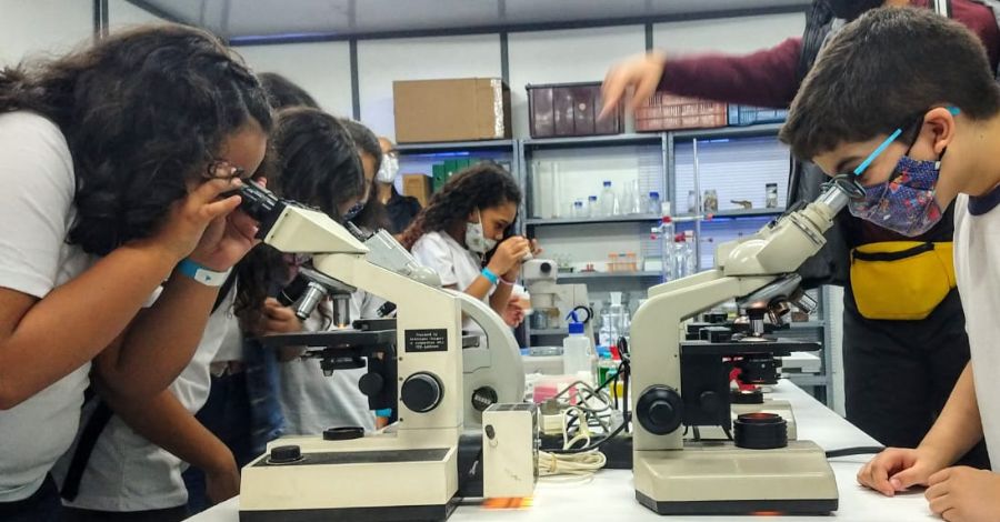 Fotografia de estudantes manuseando microscópios