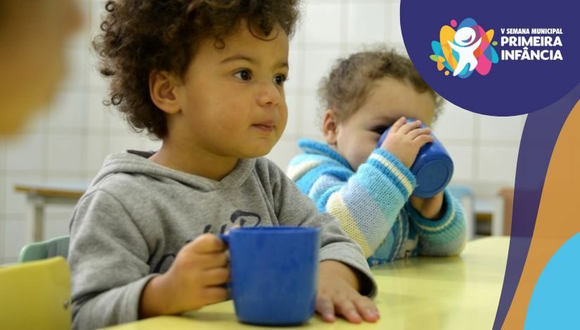 Fotografia de duas crianças pequenas se alimentando em um ambiente escolar
