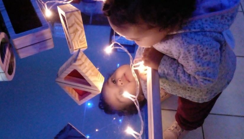Fotografia de crianças em um ambiente escuro brincando com luzes, lanternas e objetos luminosos