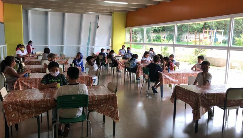 foto de Estudantes sentados em frente a mesas em pátio