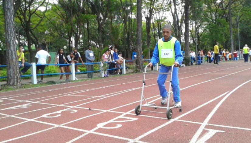 Estudante atleta paralimpico participande de corrida em pista. ele faz a prova usando andador.