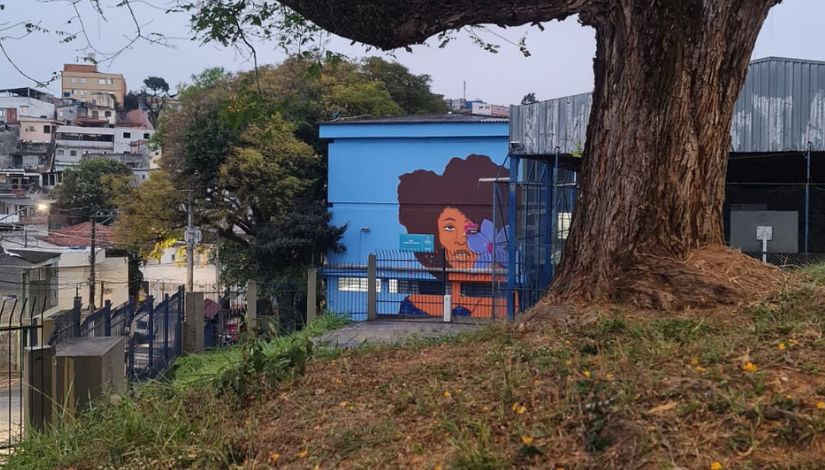 Fotografia da fachada da escola com a imagem de uma mulher negra grafitada na parede