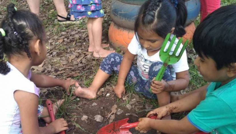 foto de 3 crianças com pás, mexendo na terra