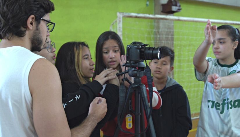 Grupo de estudantes fazem filmagens utilizando câmera filmadora 