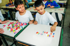 dois estudantes do 1º ano usando letras moveis na sala de aula