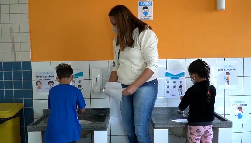 fotografia de uma mulher auxiliando crianças no processo de higiene Mães Guardiãs