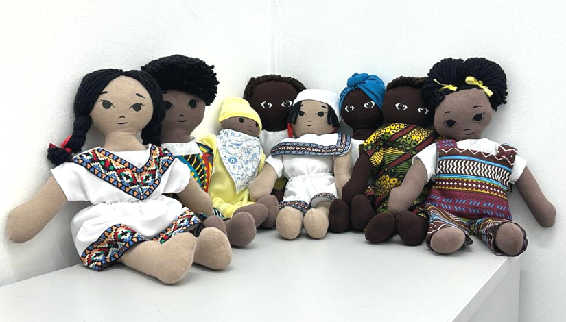 Fotografia de diversas bonecas e bonecos de pano dispostos lado a lado. Eles representam pessoas negra e andinas
