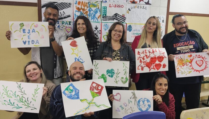 Foto de adultos segurando cartazes de desenhos em guache