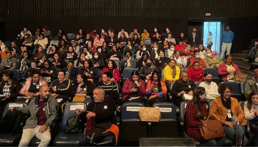 Fotografia de pessoas sentada em cadeiras de um teatro.