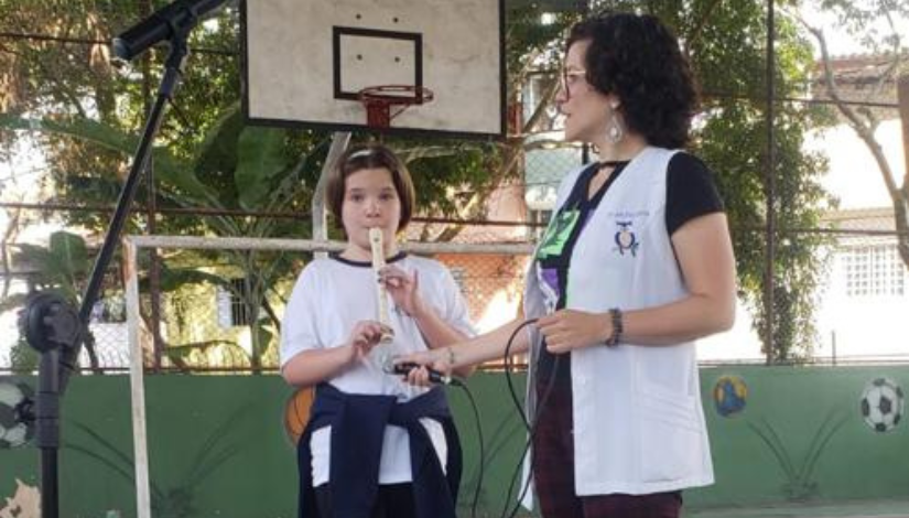 Professora Paloma Andrade ajudando a aluna que tocou flauta