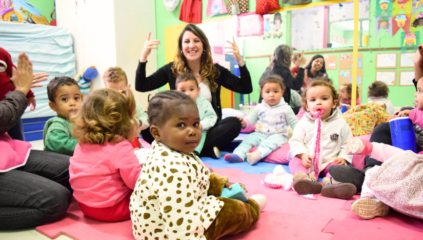 Professor De Educação Infantil com grupo de bebês em unidade educacional