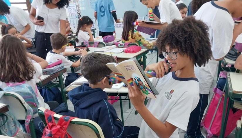 Estudante negro fazendo leitura em ambiente de sala de aula do livro 