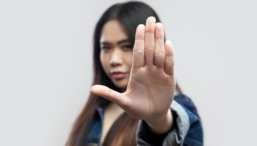 fotografia de uma mulher com o braço para frente com a mão em posição de pare.