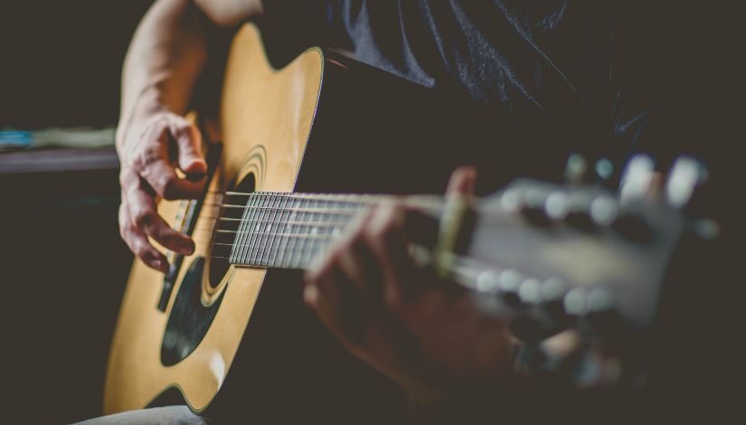 Foto de pessoa tocando violão.