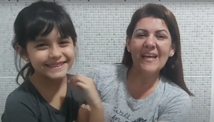 foto de uma menina e uma adulta, elas estão sorrindo. a menina é uma Estudante Surda