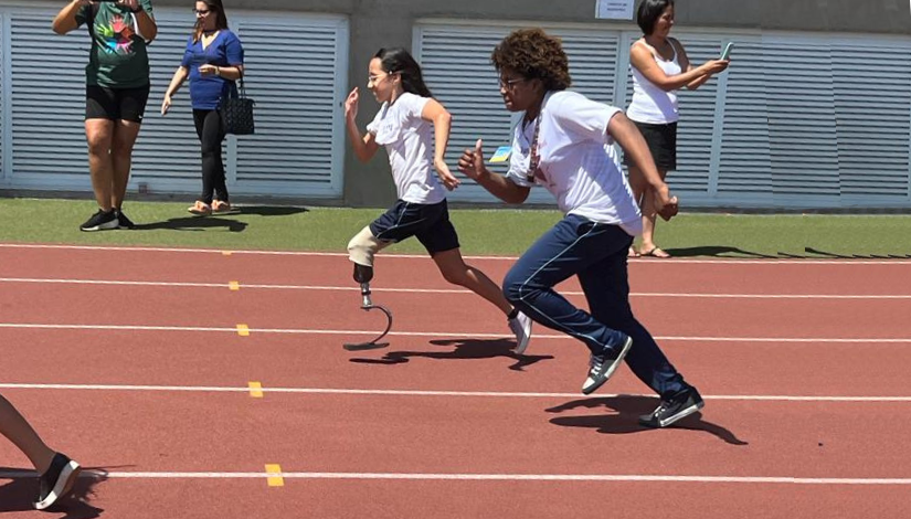 foto de duas garotas em disputa de corrida. Uma delas utiliza prótese em uma das pernas