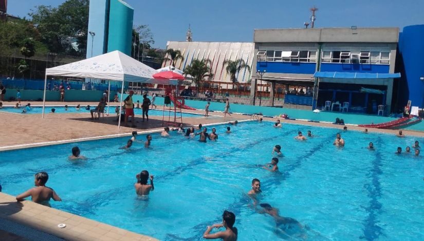 Fotografia mostra pessoas tomando banho de piscina.