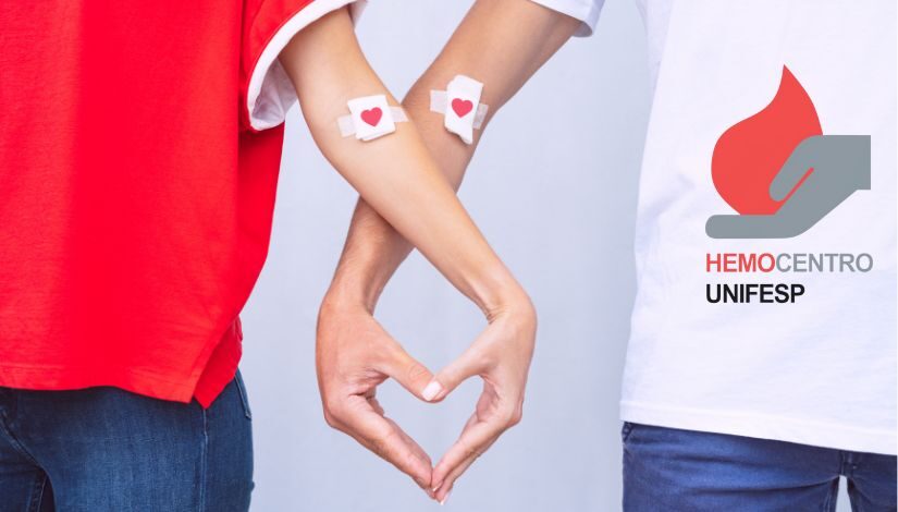 Duas pessoas com as mãos juntas formando um coração. Em seus braços há um curativo com um coração. Em uma das camisetas há a logotipo do Hemocentro UNIFESP.