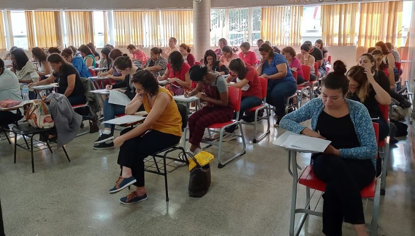 Diversas pessoas estão sentadas em uma sala de aula.